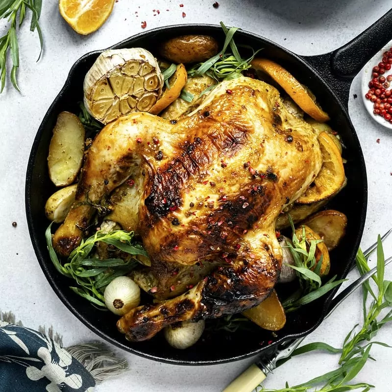 Poulet rôti dans une casserole en fonte accompagné de légumes