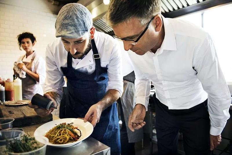 Cuisiniers préparant à manger entrain de dresser une assiette avec de la servir