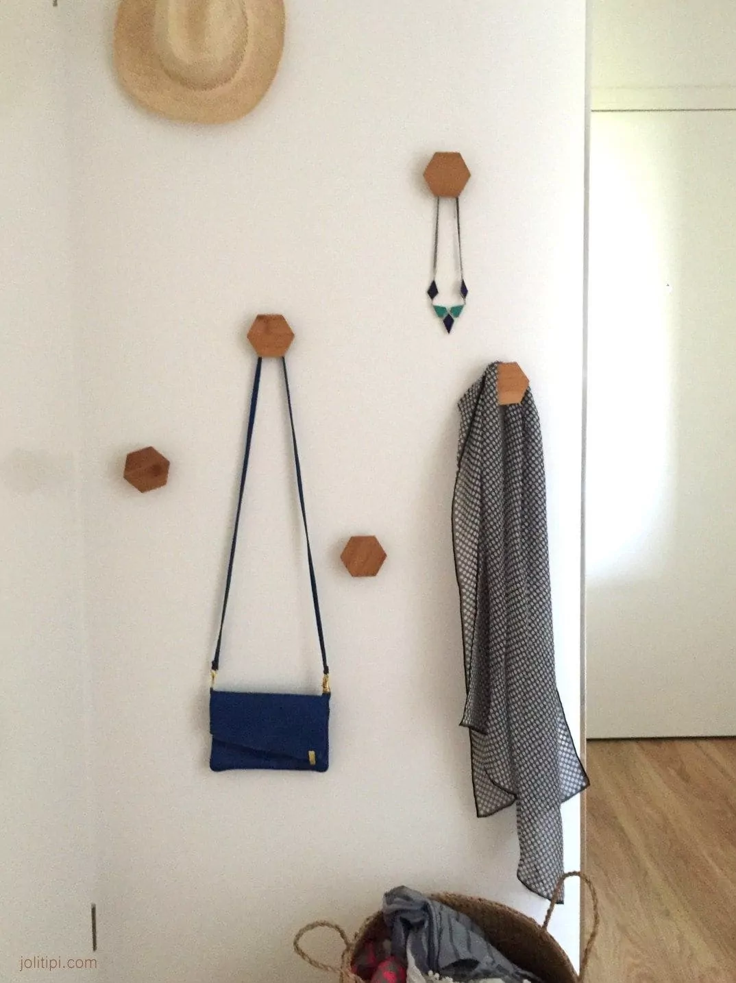 Mur avec des patères en bois utilisées comme support pour un sac à main ainsi qu'une veste